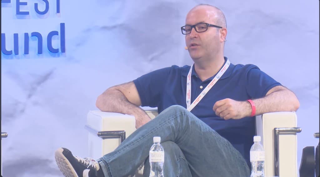 Freddy Friedman on stage in a panel chair with headset microphone